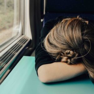 eerste teken van de zwangerschap kan vermoeidheid zijn zoals deze vrouw die in de trein in slaap is gevallen